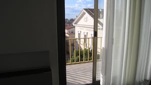 Vista através de uma porta com varanda, um edifício com a placa 'TEATRO GIORDANO' e céu claro.