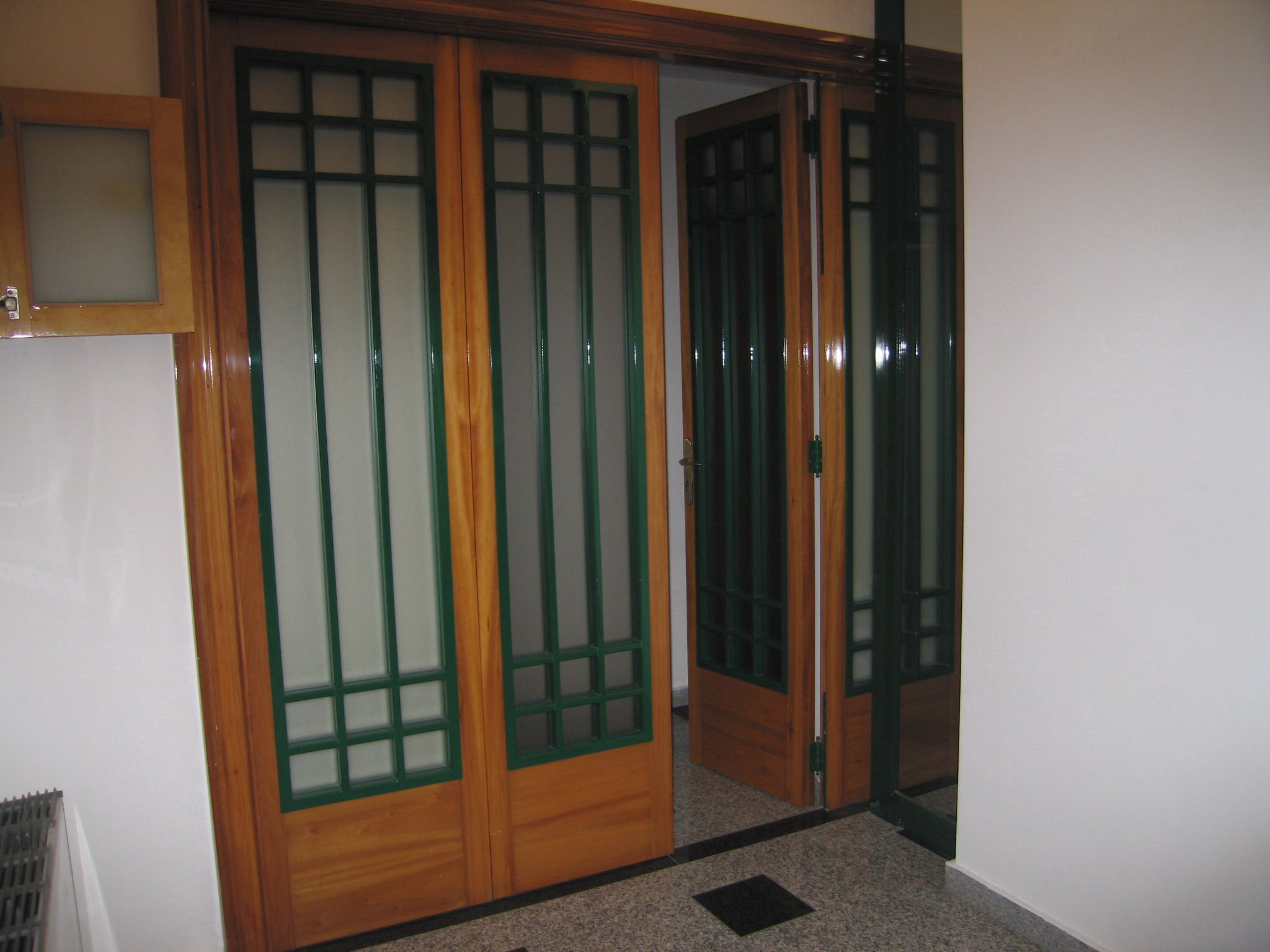 Een houten schuifdeur met een glazen ruit, die leidt naar een kamer met een vloerbedekking.