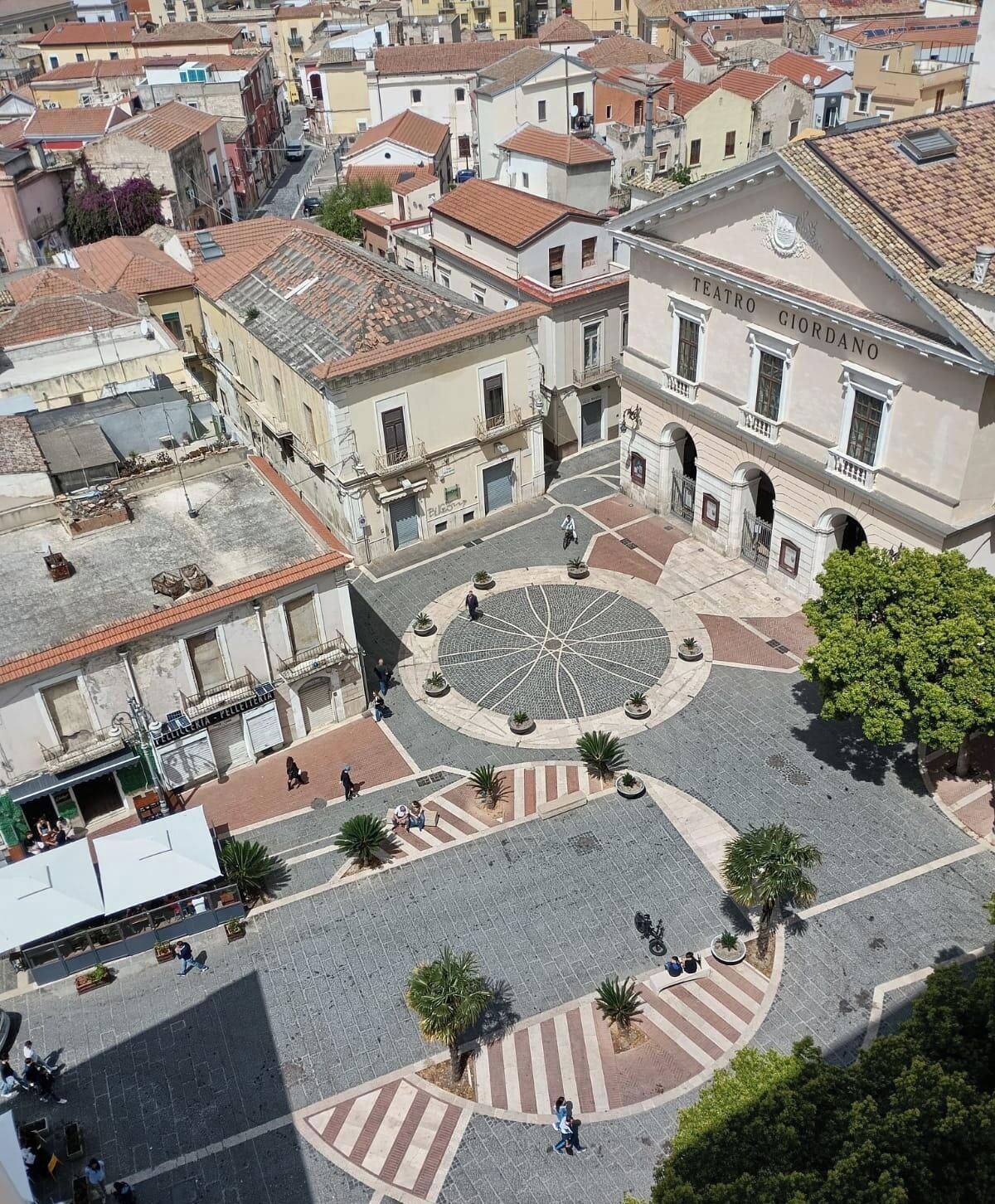 A plaza with a central circular design, surrounded by buildings with traditional architecture.