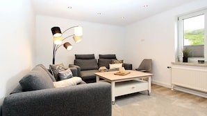 Ein modernes Wohnzimmer mit einem grauen Sofa, einem Couchtisch und einer Stehlampe.