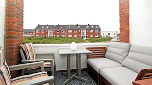 Ein Balkon mit einer Couch, Stühlen und einem kleinen Tisch.
