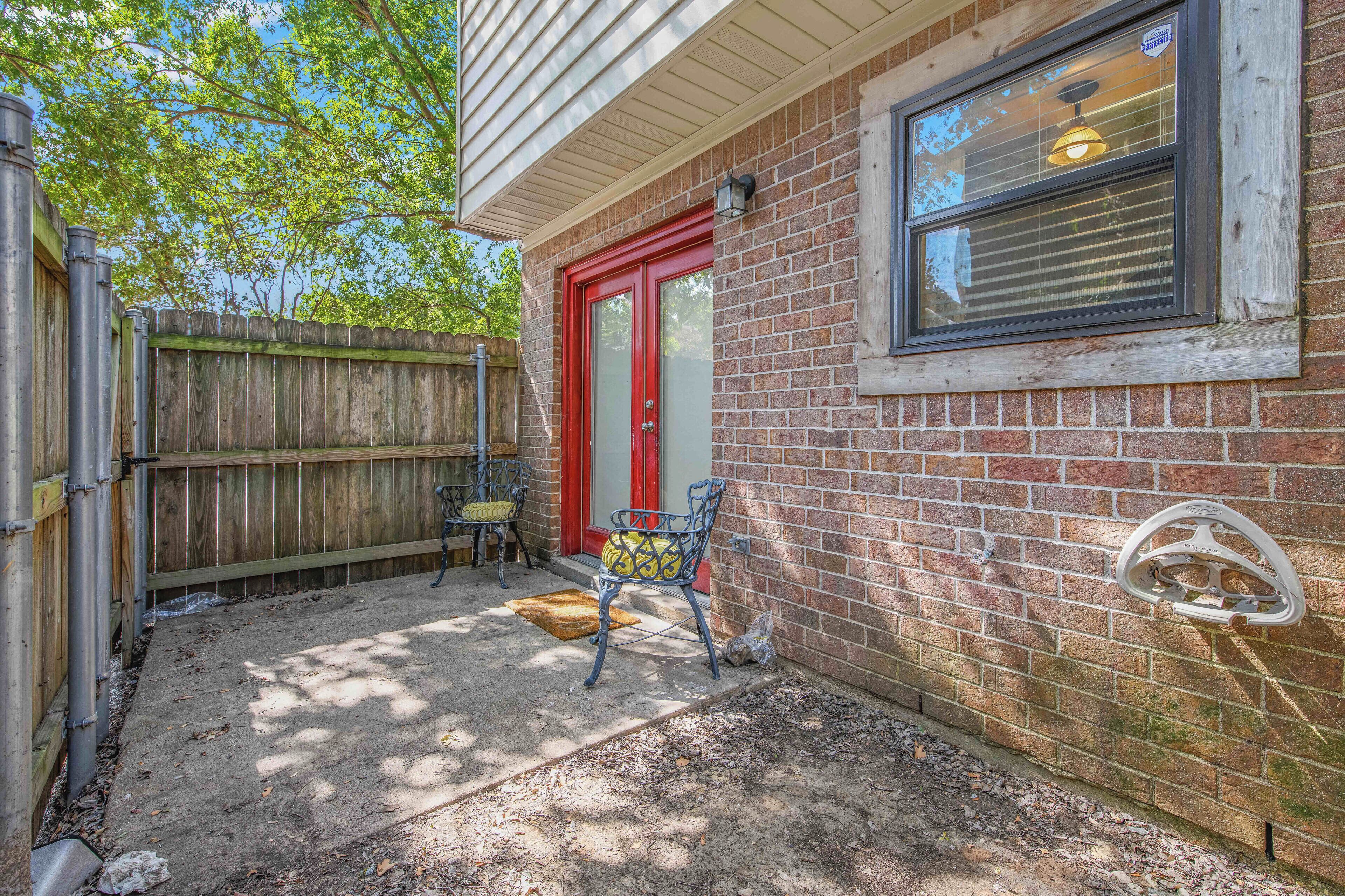 A residential property with a brick exterior, a red door, and a window with a light fixture.