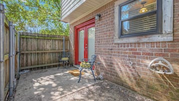 A residential property with a brick exterior, a red door, and a window with a light fixture.