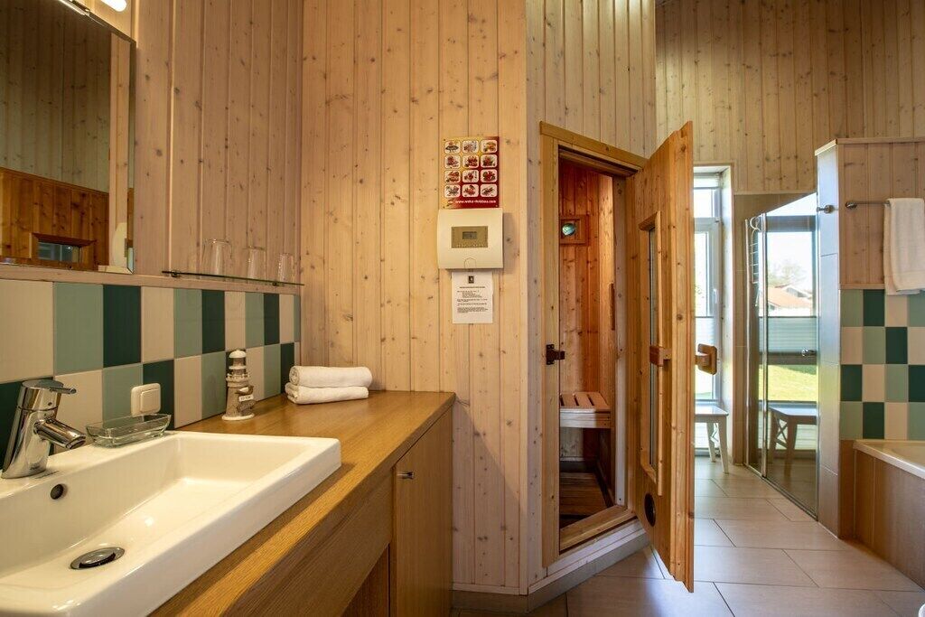 A wooden interior with a sink, mirror, and a wooden door leading to a shower area.