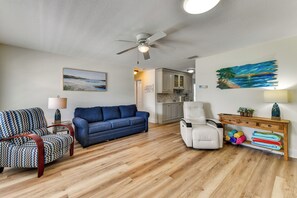 A living room with a blue sofa, a patterned armchair, a white recliner, and a wooden coffee table with towels. - Canal-Front Gem w/ Dock & Guest Home in Cortez! (Cortez)