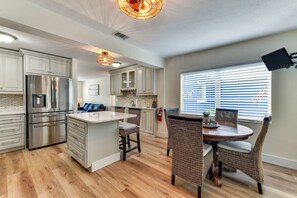 A modern kitchen with stainless steel appliances, a central island, and wicker chairs. - Canal-Front Gem w/ Dock & Guest Home in Cortez! (Cortez)