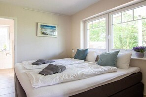 Ein Schlafzimmer mit zwei Betten, einem Fenster mit Blick auf Grünflächen und einem Bild an der Wand.