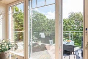 Ein Balkon mit Glastür, einem Korbstuhl und einem Tisch mit Obst.