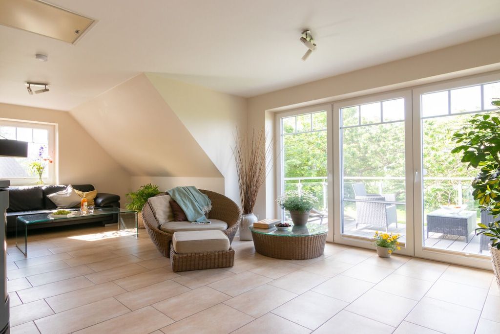 A spacious living area with a sofa, armchair, and coffee table, a large sliding glass door to an outdoor patio, and a ceiling fan.