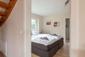 A bedroom with a bed, a window, and a door leading to a bathroom. - Holiday home with 3 bedrooms (Dagebüll OT Süderwaygaard)