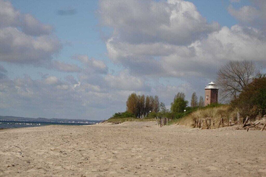 A sandy beach with a lighthouse on a hill.