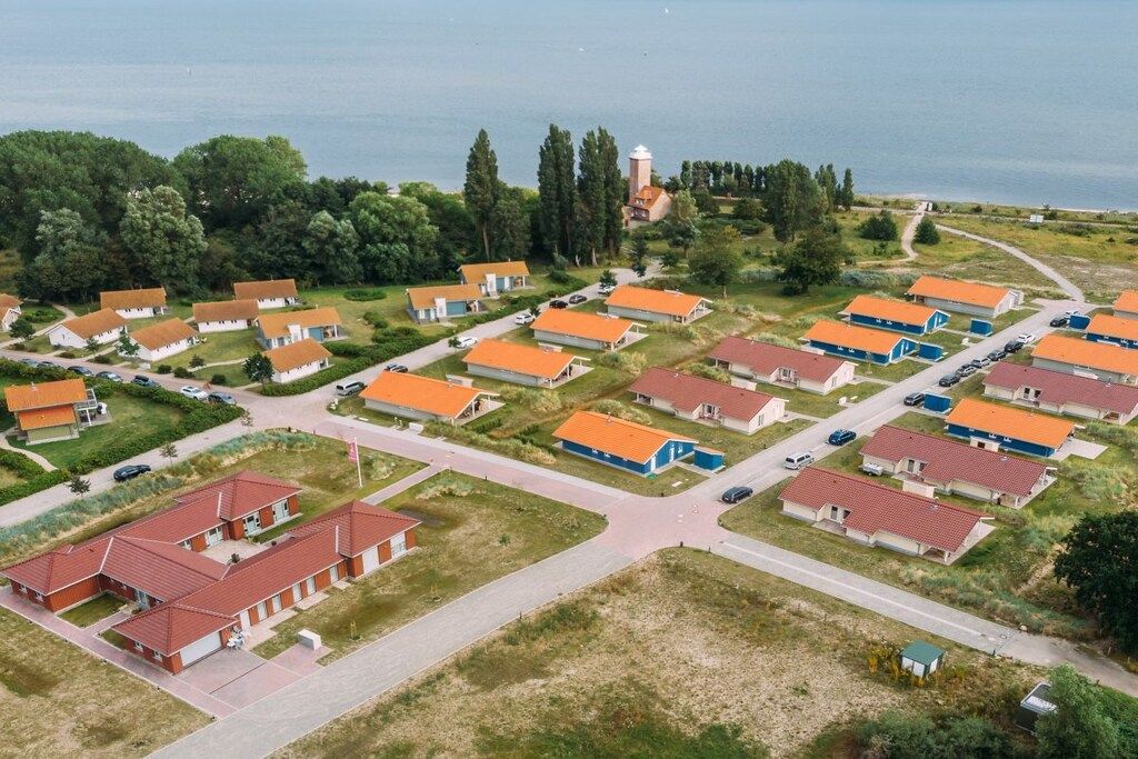 Un quartier résidentiel composé de plusieurs maisons, une rue principale et une étendue d’eau en arrière-plan.