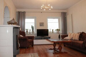 Ein Wohnzimmer mit Kamin, Fernseher, Sofa und einer Chandelier.