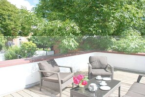 A rooftop terrace with wicker furniture and a table set for two. - Holiday apartment with 1 bedroom (Husum\/ Nordsee)