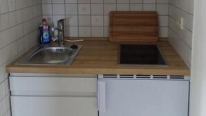 Une cuisine de taille réduite équipée d’un évier, d’une planche à découper et d’un lave-vaisselle.