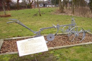 Eine Metallskulptur in einer grünen Wiese mit einem Schild.