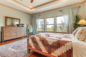 Ein Schlafzimmer mit einem großen Bett, einem Schminktisch, einem Spiegel und einem Fenster mit Vorhängen.