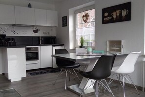 Una cocina moderna con armarios blancos, una isla central con sillas y un ventanal con vistas.