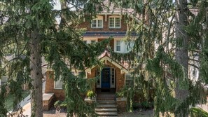 A two-story house with a front porch, a blue door, and a brick facade. - SpaciousStay- Game Room - NearClinic & UniversityCircle (Cleveland Heights)