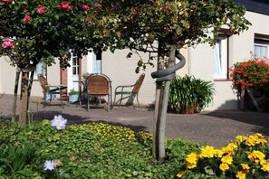 Ein Garten mit einer Bank, Stühlen und einem Tisch.