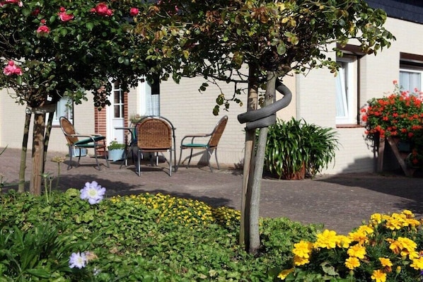 Un jardin avec un banc, des chaises et une table.