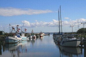 Un port de plaisance où sont amarrés différents types de bateaux, avec une eau calme et un ciel dégagé.