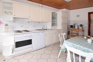 Une cuisine compacte avec des meubles blancs, un four encastré et un four à micro-ondes.