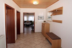Un couloir avec des portes en bois, un banc et un meuble.