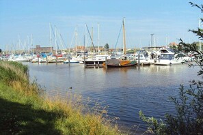 Un port de plaisance où sont amarrés différents types de bateaux, avec une eau calme et un bâtiment visible à l’arrière-plan.
