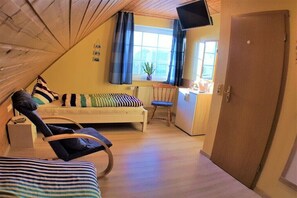 A cozy room with a bed, a chair, a desk, and a television. - Holiday apartment with 2 bedrooms (Carolinensiel)