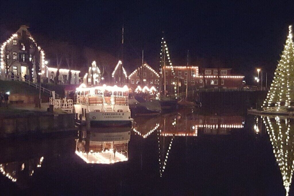 A waterfront scene with illuminated buildings and a boat docked at the pier.