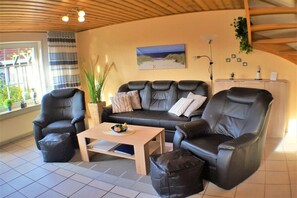 A living room with a sofa, two armchairs, a coffee table, and a potted plant. - Holiday apartment with 2 bedrooms (Carolinensiel)