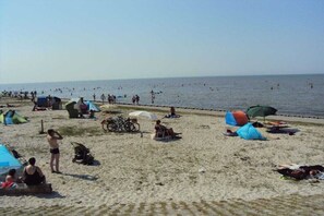 Ein Strand mit Zelten, Sonnenschirmen und Menschen.