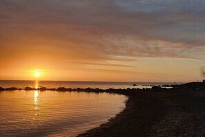Ein Sonnenuntergang über einem Strand mit felsigem Ufer und ruhiger See.