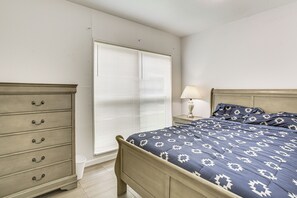 A bedroom with a bed, a nightstand, a lamp, and a dresser.