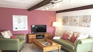 Een woonkamer met een televisie, bank en salontafel.