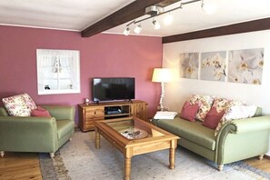 Ein Wohnzimmer mit Fernseher, Sofa und Couchtisch.