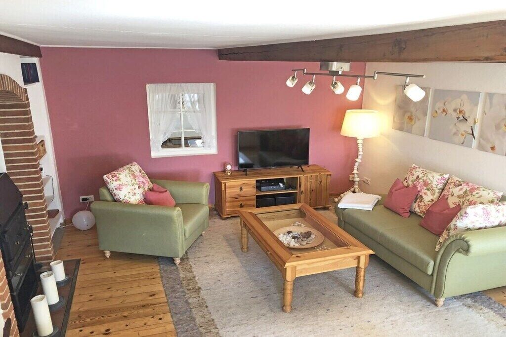 A living room with a television, two sofas, a coffee table, and a fireplace.