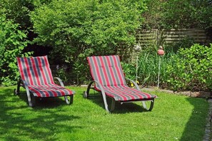 Two striped lounge chairs in a grassy garden area with a wooden fence and greenery in the background. - Rikate in Kappeln on the Schlei (Kappeln Stadt)