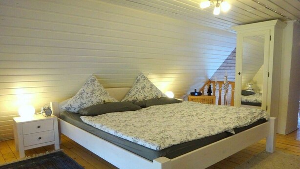 Een slaapkamer met een bed, nachtkastje en bedlampje.