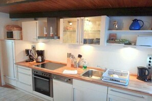 A compact kitchen with a dishwasher, oven, and a coffee maker on the countertop. - Rikate in Kappeln on the Schlei (Kappeln Stadt)