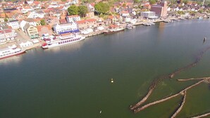 Luchtbeeld van een stad aan de rivier, met gebouwen, een grote boot afgemeerd en een brug.
