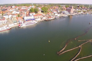 Eine Luftaufnahme einer Flussstadt mit Gebäuden, einem vertäuten großen Boot und einer Brücke.