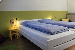 A twin bed with a wooden headboard, a small bedside table, and a green rug. - Holiday home in Dangast with swimming pool (Dangast)
