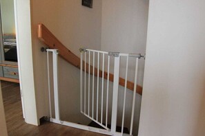 A white baby gate installed at the top of a wooden staircase. - Holiday home in Dangast with swimming pool (Dangast)