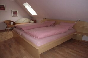 Ein Schlafzimmer mit einem hölzernen Bett, einem Sessel und einem Oberlicht.