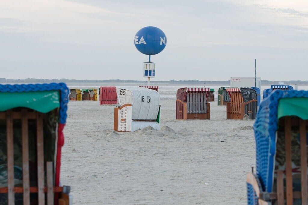 A beach with beach chairs and a blue weather station.