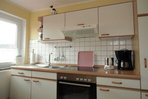 Une cuisine avec des meubles blancs, une cuisinière, un évier et une machine à café.