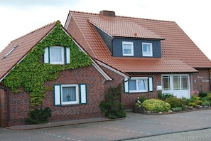 Ein zweistöckiges Haus mit geneigtem Dach, einem kleinen Dachfenster und einer Ziegelaußenwand.