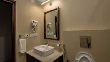 Ein Badezimmer mit Waschbecken, Spiegel, Fön und Toilette.